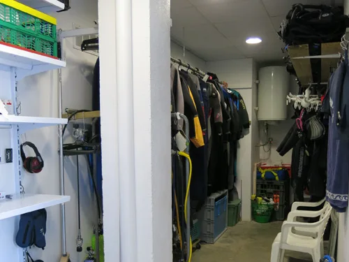 Intérieur d'un local de plongée avec combinaisons, gilets et accessoires