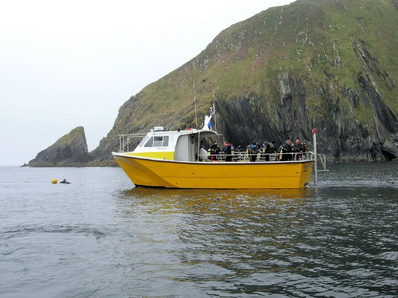 Bateau de plongée jaune en mer avec des plongeurs équipés