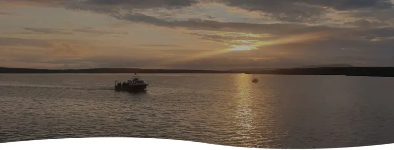 Deux bateaux naviguent sur une mer calme au coucher du soleil