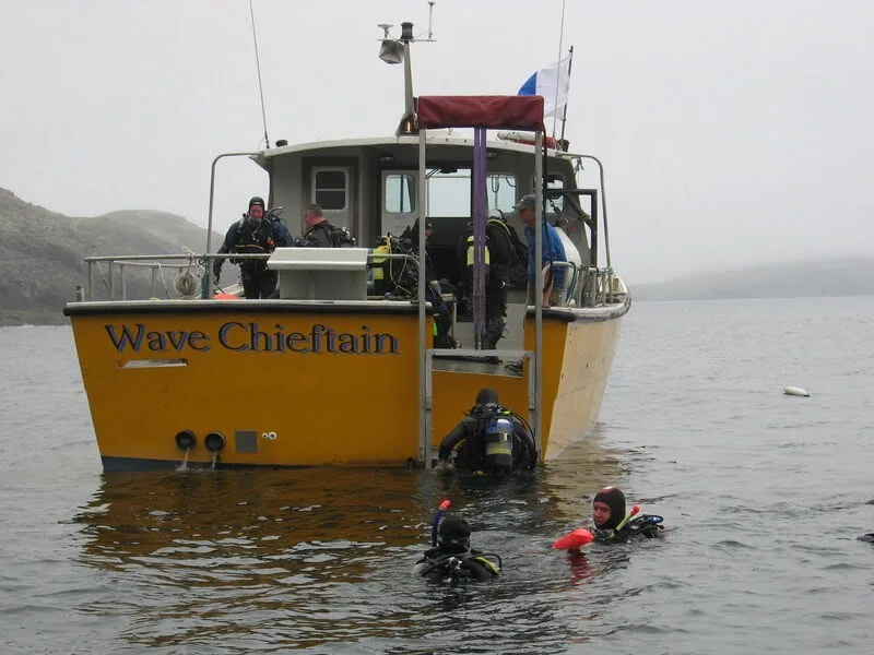 Plongeurs s'équipent près d'un bateau jaune en mer, temps nuageux
