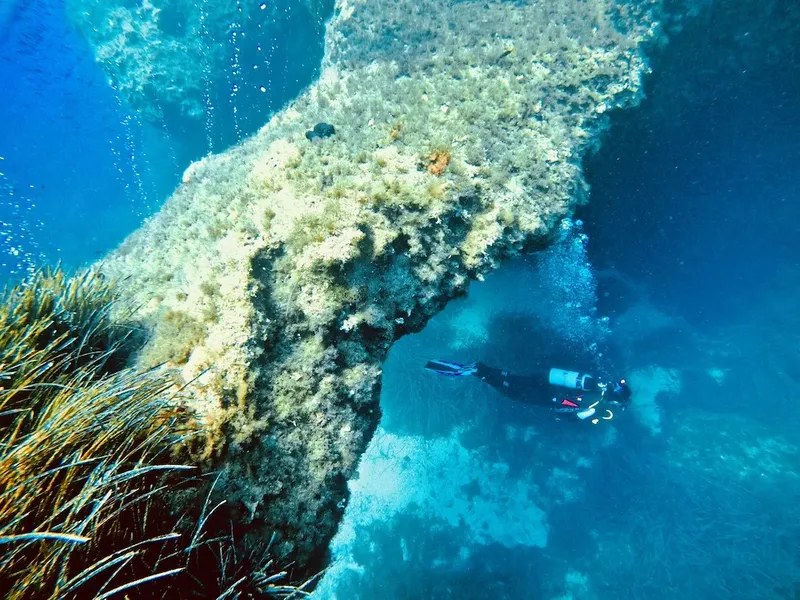 Plongeur explorant une structure rocheuse sous-marine avec de la posidonie