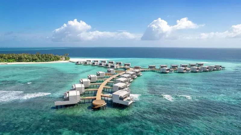 Vue aérienne d'un complexe hôtelier sur pilotis dans une eau turquoise