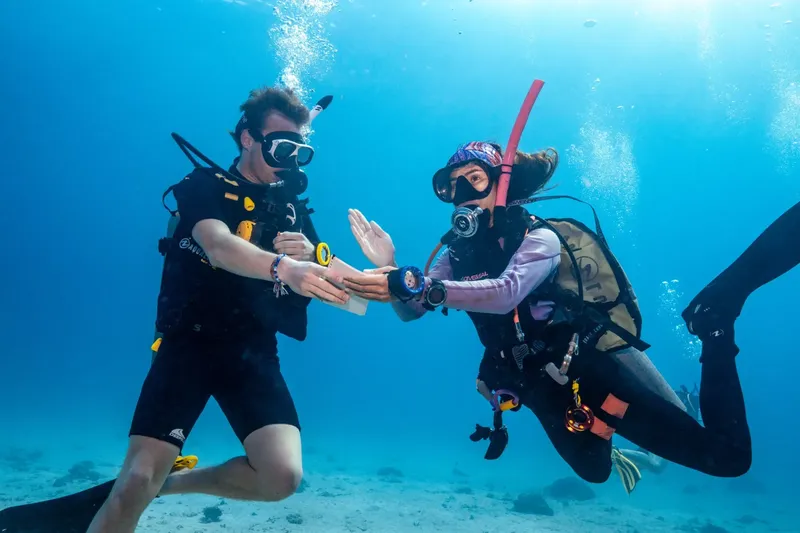 Deux plongeurs s'échangent un objet sous l'eau en toute sécurité