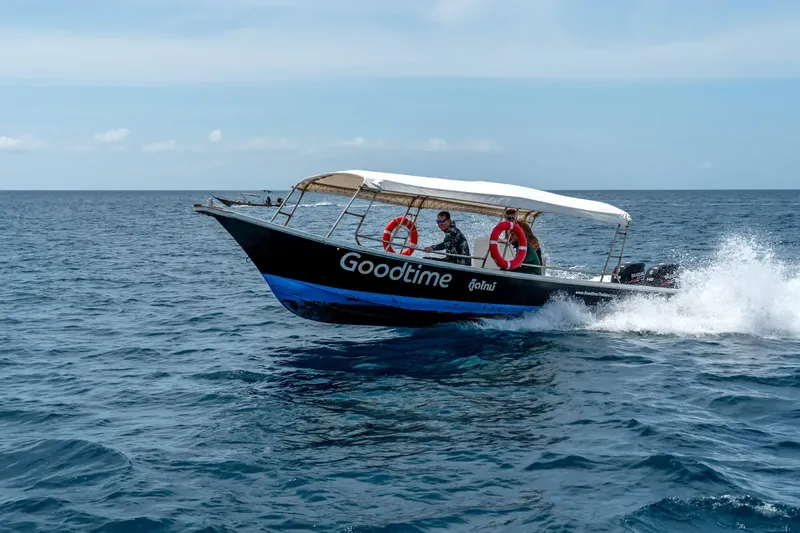 Bateau de plongée noir et bleu navigue sur une mer calme
