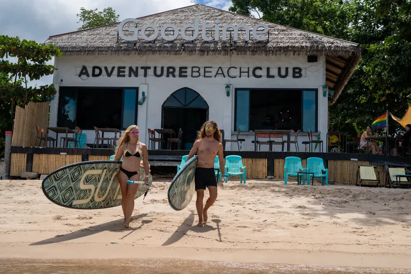 Deux personnes portant des planches de surf marchent sur une plage