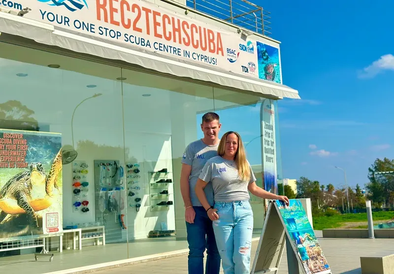 Devanture d'un centre de plongée avec deux personnes souriantes
