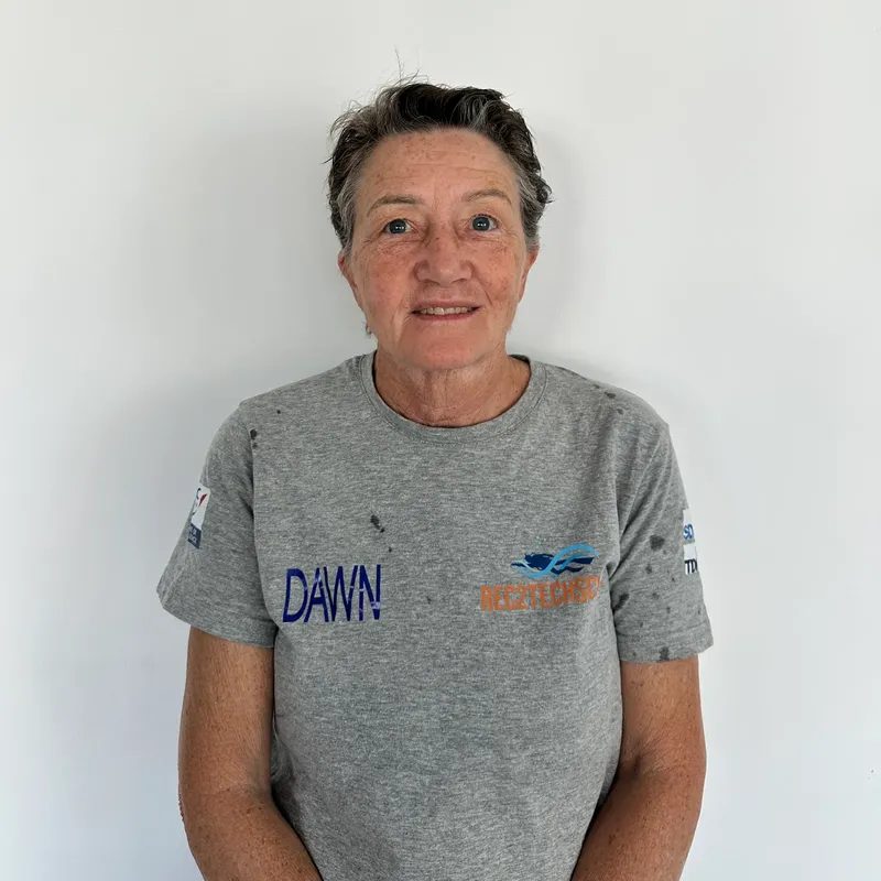 Portrait d'une femme souriante, portant un t-shirt gris avec des logos