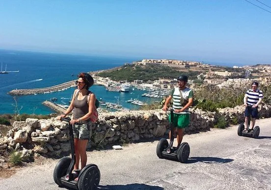 Trois personnes sur des gyropodes avec vue sur un port de plaisance