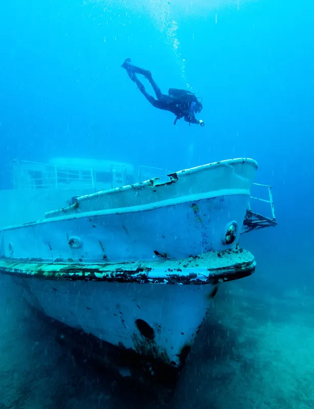 Plongeur explorant l'épave d'un bateau blanc au fond de la mer