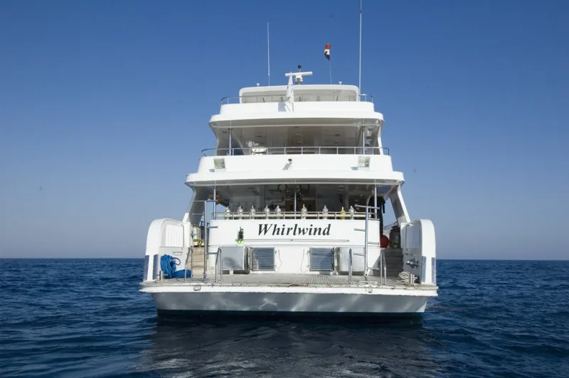Bateau de plongée blanc sur mer bleue, vue arrière avec nom