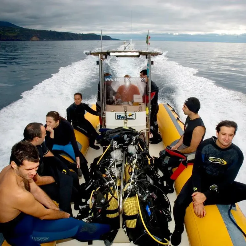 Groupe de plongeurs souriants à bord d'un bateau semi-rigide jaune