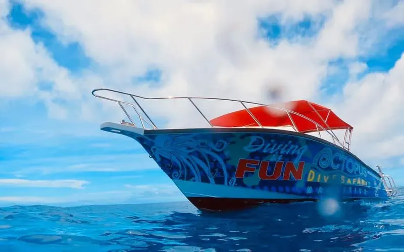 Bateau de plongée rouge et blanc sur une mer bleue sous ciel nuageux