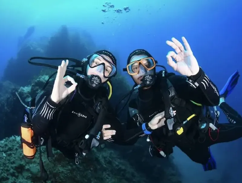 Deux plongeurs souriants font des signes de validation sous l'eau