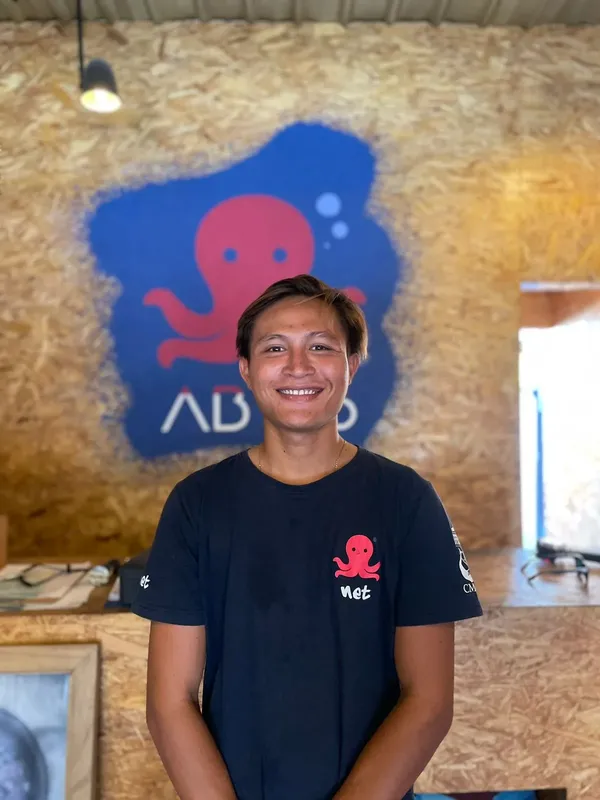 Portrait d'un homme souriant devant une peinture de poulpe bleue