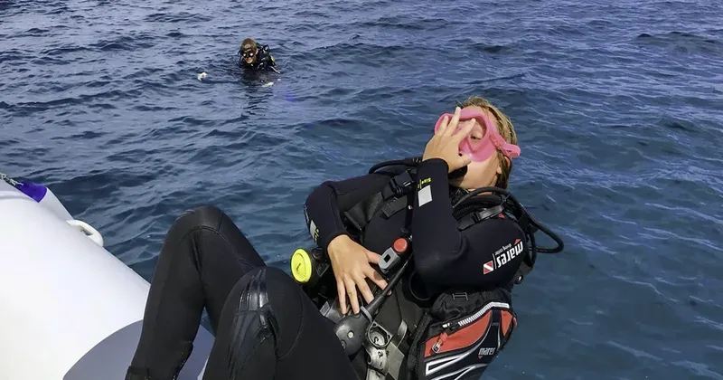 Plongeuse se reposant sur un bateau pneumatique en combinaison complète