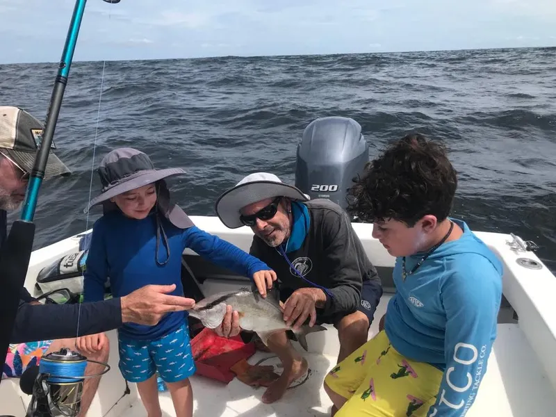 Quatre personnes sur un bateau regardent un poisson capturé