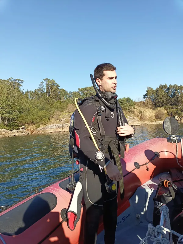 Plongeur en combinaison complète se tenant sur un bateau orange
