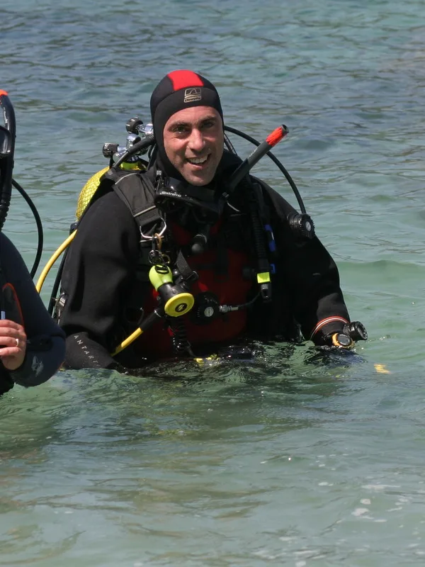 Plongeur souriant émerge de l'eau avec son équipement complet