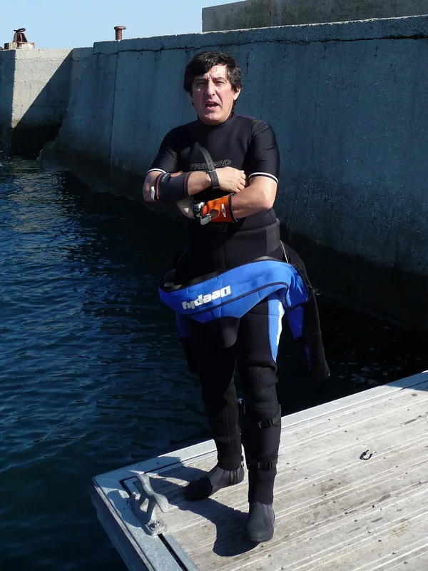 Plongeur en combinaison sur un ponton, prêt à plonger dans la mer
