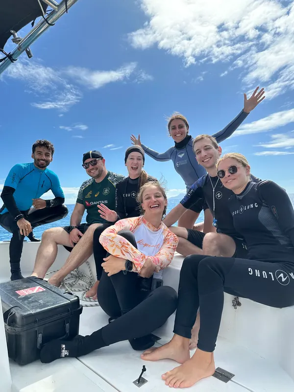Groupe de plongeurs souriants posant sur le pont d'un bateau en mer