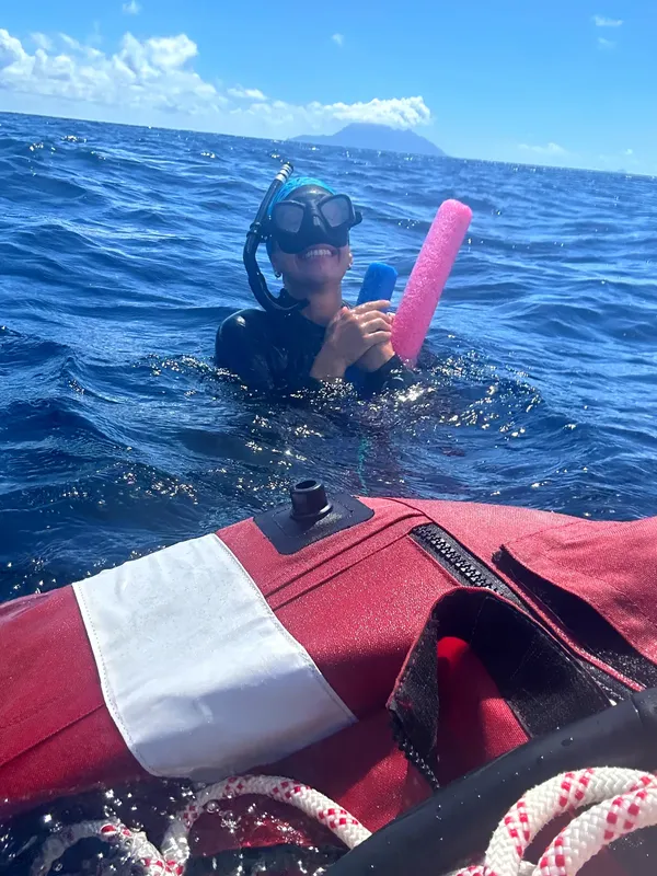 Plongeur souriant émerge de l'eau près d'un bateau rouge vif