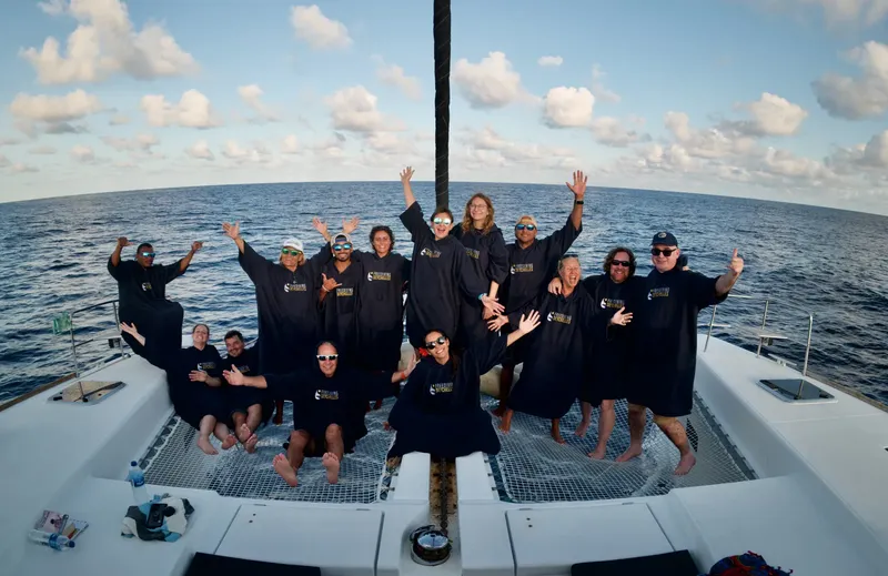 Groupe de personnes souriantes sur le pont d'un catamaran en mer