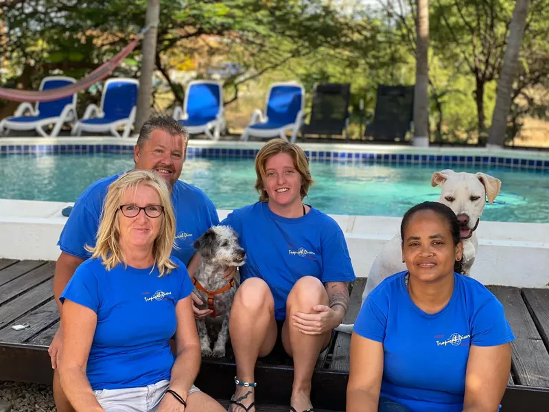 Quatre personnes souriantes posent avec un chien près d'une piscine