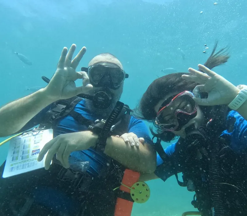 Deux plongeurs souriants font des signes de victoire sous l'eau