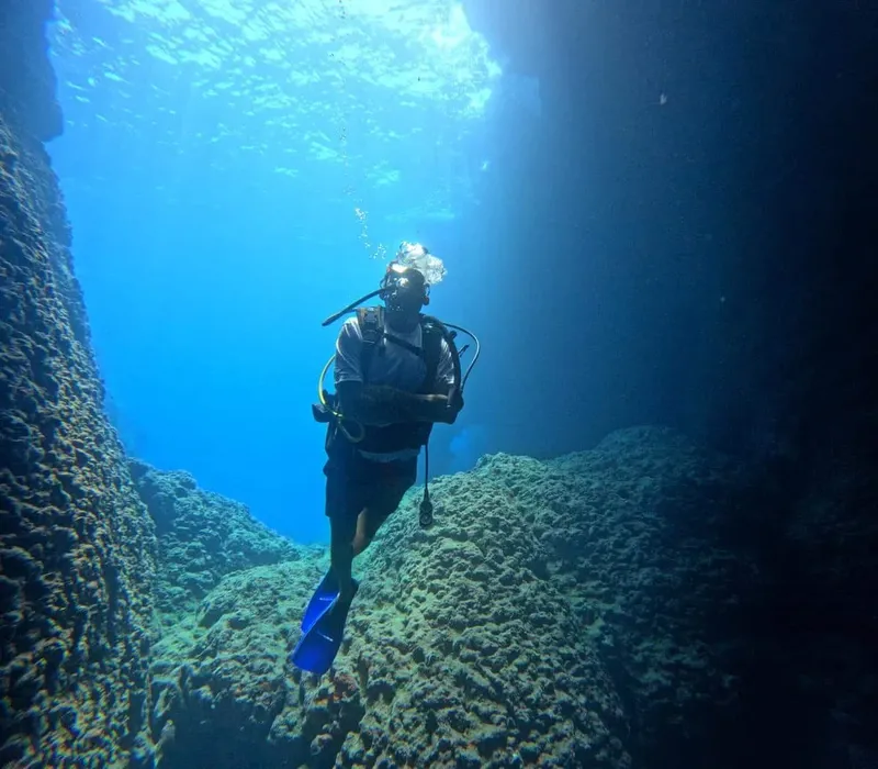 Plongeur explorant une grotte sous-marine avec une lumière descendante