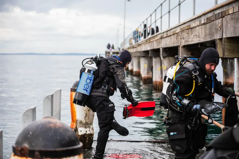 Plongeurs s'équipent au bord de l'eau sur un ponton gris