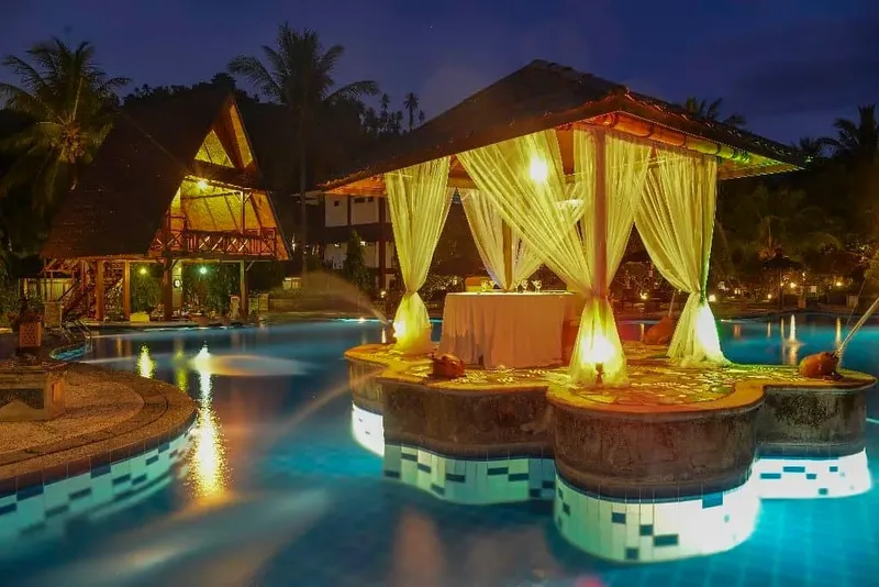 Bâtiment exotique au bord d'une piscine illuminée, ambiance tropicale nocturne