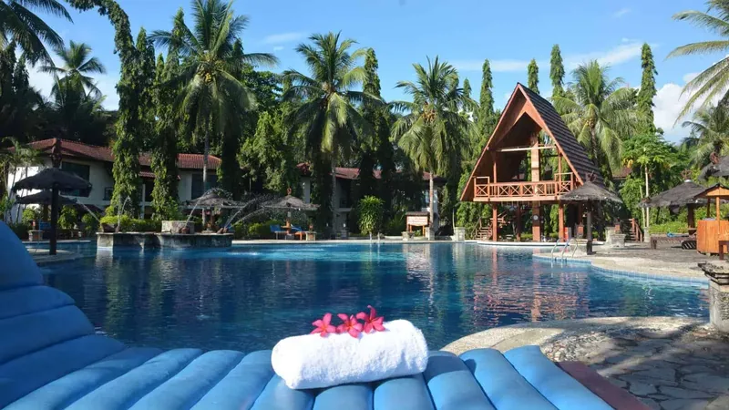 Piscine d'un centre de vacances tropical avec bâtiments et végétation luxuriante