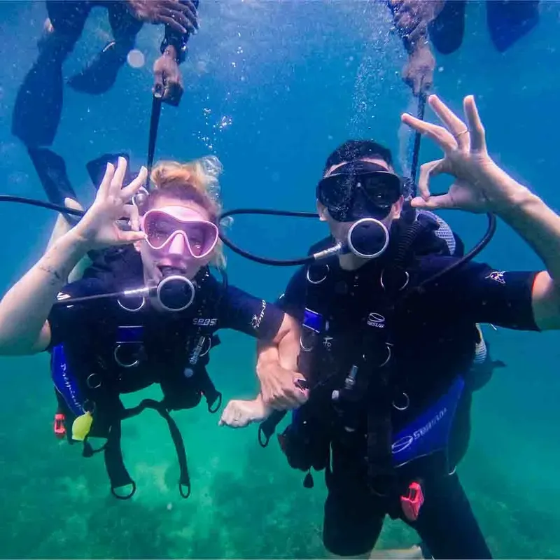 Deux plongeurs souriants font des signes de paix sous l'eau
