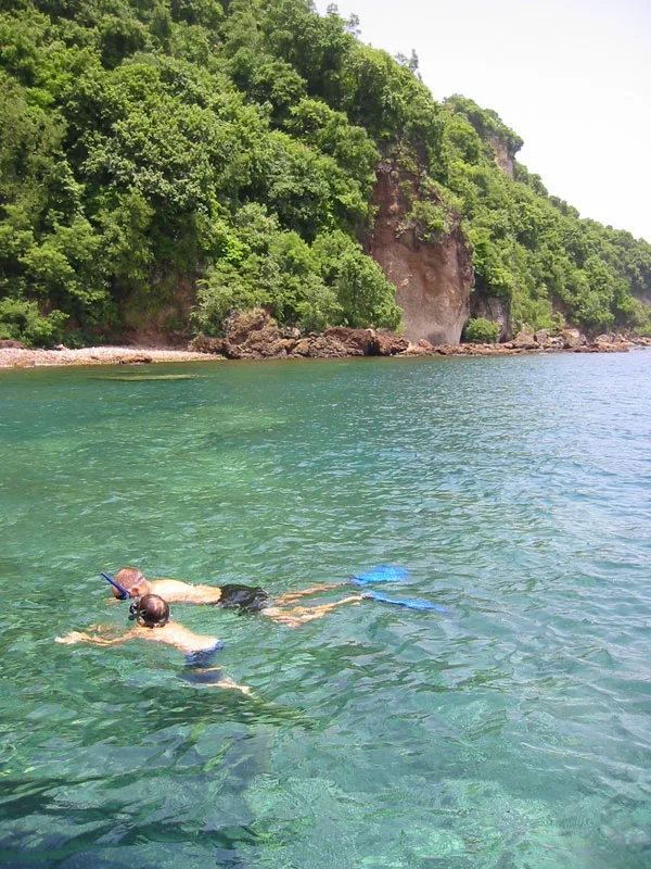 Personne en snorkeling dans une eau turquoise face à une côte rocheuse