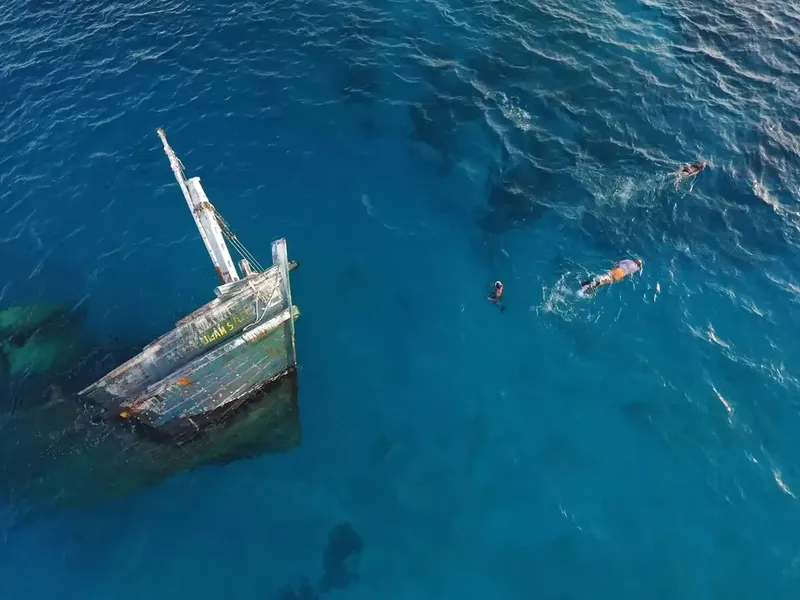Plongeurs explorent l'épave d'un bateau coulé en mer bleue