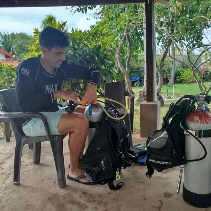 Un plongeur assis vérifie son équipement de plongée sur une chaise