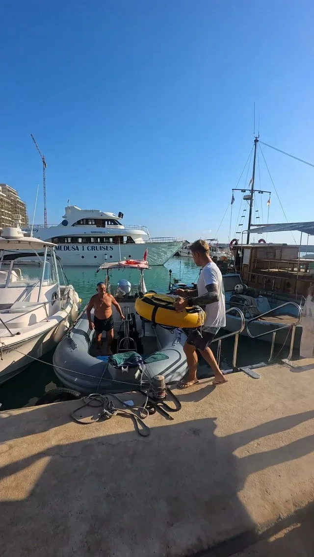 Deux hommes sur un quai près de bateaux et d'un zodiac jaune