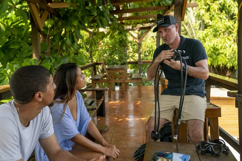 Instructeur de plongée explique l'utilisation du matériel à deux élèves