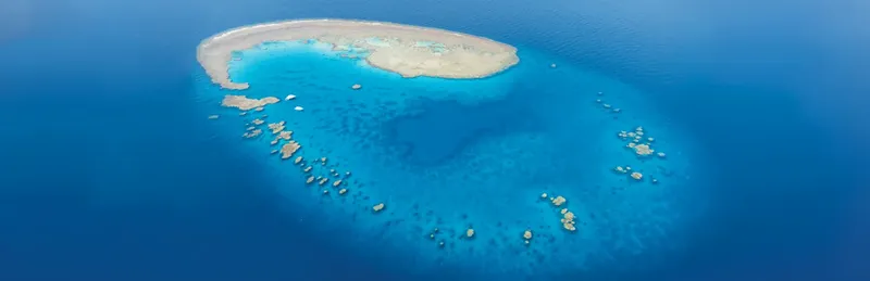 Vue aérienne d'un récif corallien turquoise entouré d'eaux bleues profondes