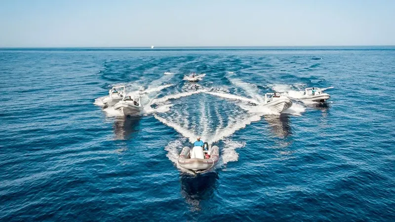 Plusieurs bateaux semi-rigides naviguent rapidement sur une mer bleue calme