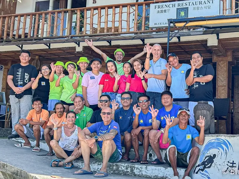 Groupe de personnes souriantes posant devant un restaurant en bord de mer