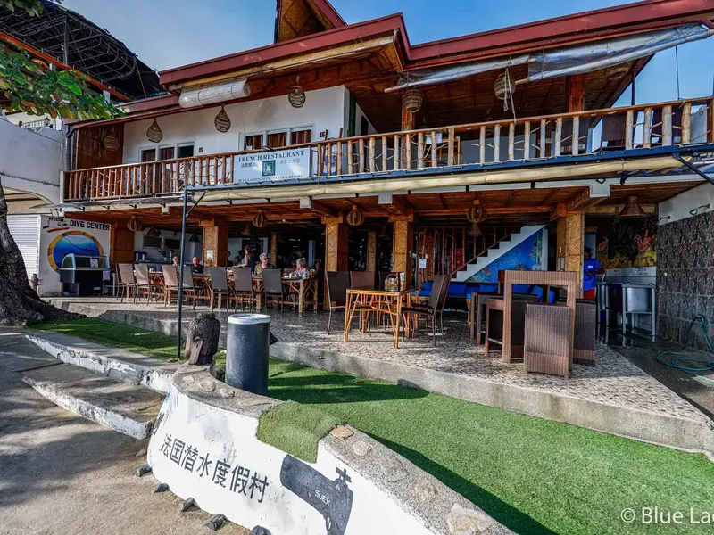 Façade d'un centre de plongée avec terrasse et quelques personnes assises