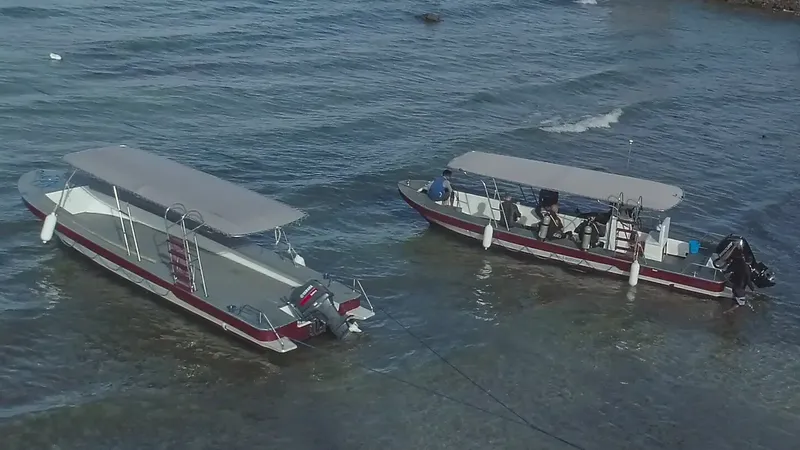 Deux bateaux de plongée amarrés dans une eau claire et peu profonde