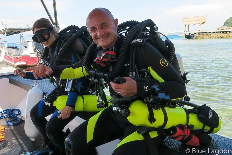 Deux plongeurs souriants équipés sur un bateau de plongée ensoleillé