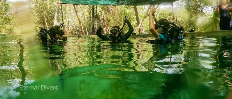 Trois plongeurs en formation dans une piscine, équipement complet visible