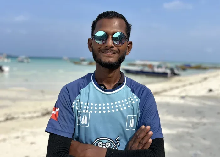 Un homme souriant porte des lunettes de soleil sur une plage