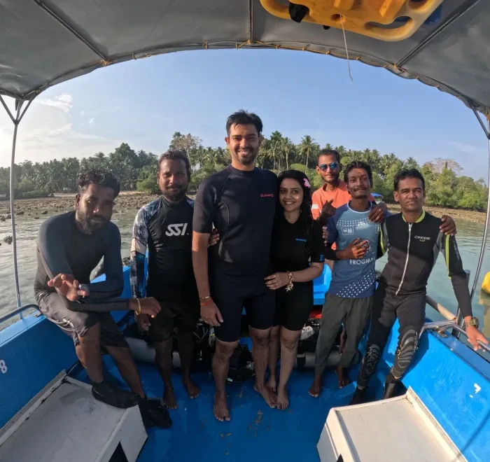 Groupe de plongeurs souriants à bord d'un bateau bleu en mer