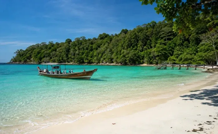 Plage de sable blanc, bateau longtail et eau turquoise ensoleillée