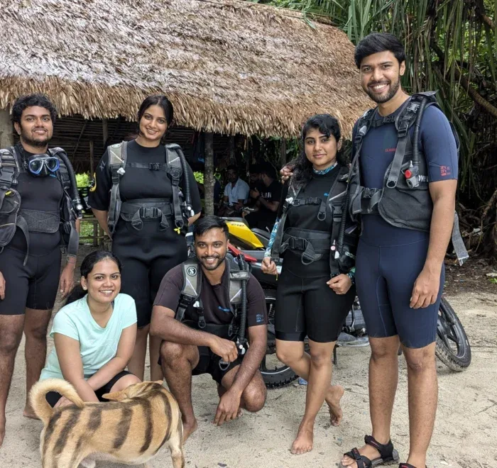Groupe de plongeurs souriants équipés sur une plage tropicale ensoleillée