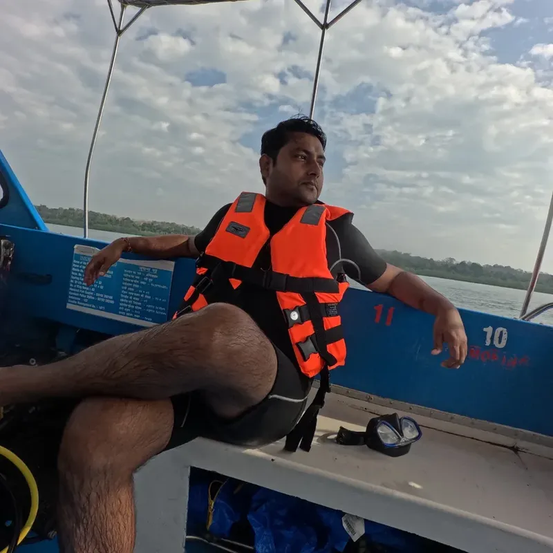 Homme assis sur un bateau de plongée, portant un gilet de sauvetage orange